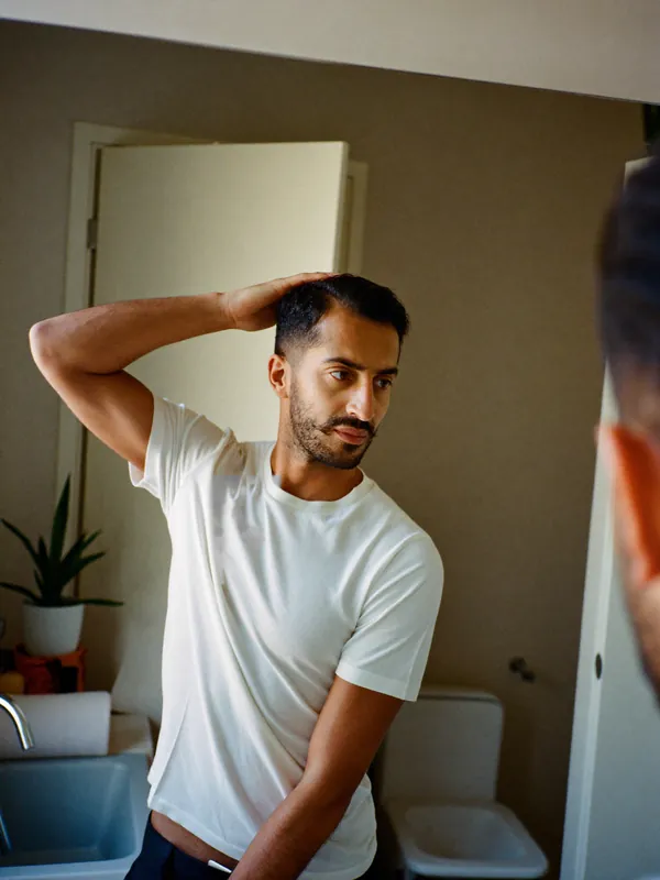 A man checking his hairline in the mirror